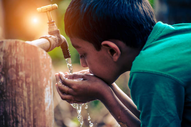indian boy drinking tap water outside